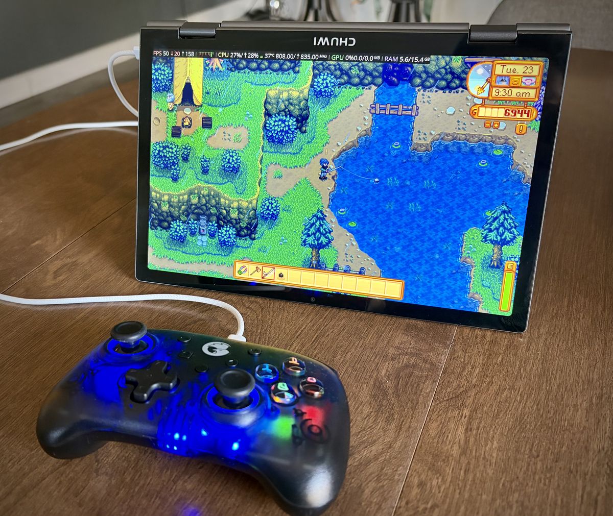 A folded laptop in 'tent' mode and a controller, with Stardew Valley on the screen.