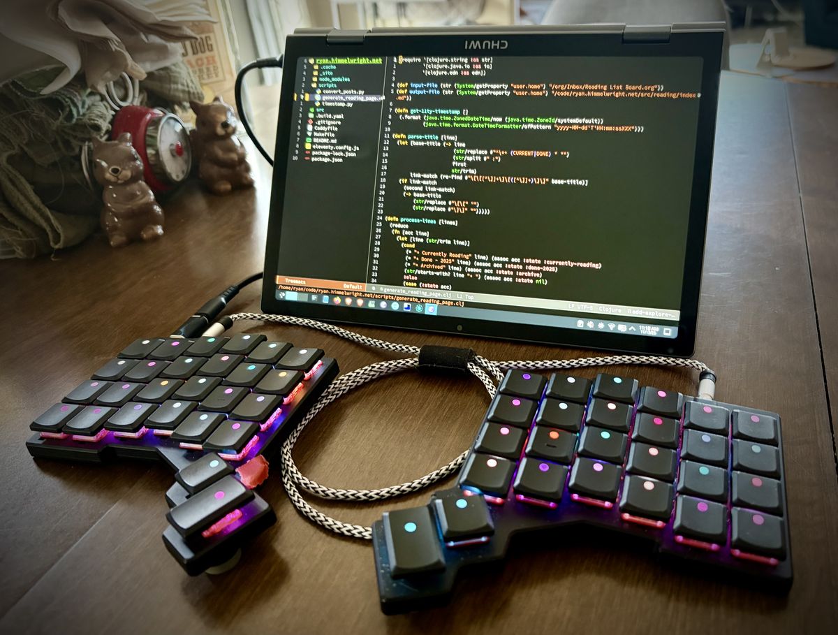 The Minibook in tent mode, with the ZSA Voyager split keyboard attached, editing code.