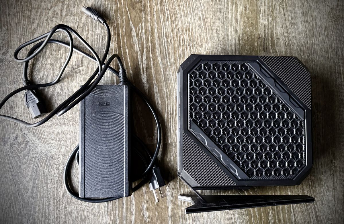 A mini computer on its side, with a giant cable and power brick next to it.
