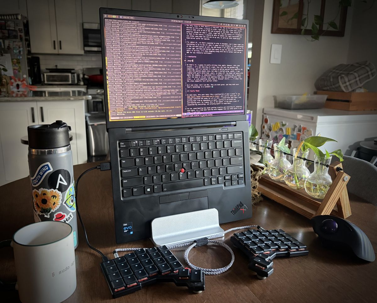 A Thinkpad vertically in a stand with a split keyboard