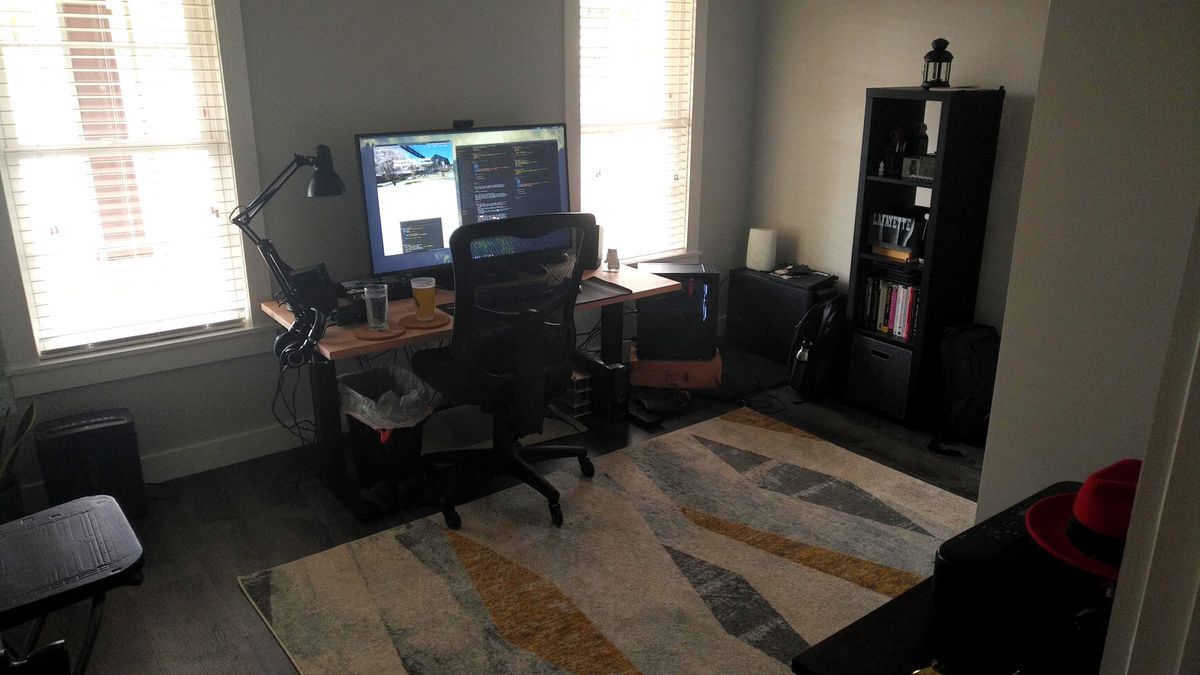 A desk in a plain room with a large monitor