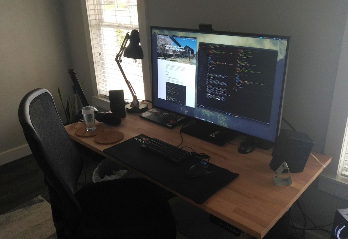 A closer picure of a large desk with an even larger monitor, in a plain room