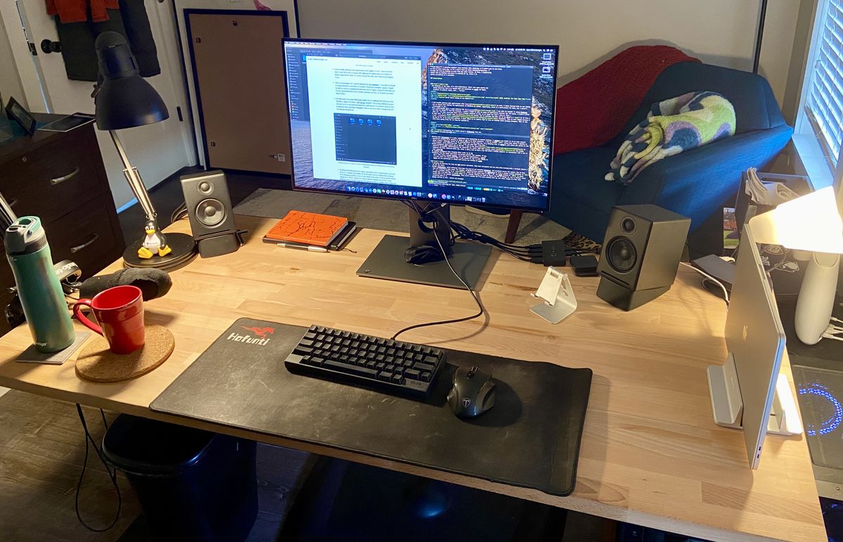 A large wooden desk, with a computer setup