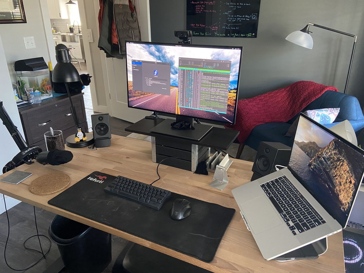 A closer look at the wooden desk, with a monitor on a box, and macbook on a stand