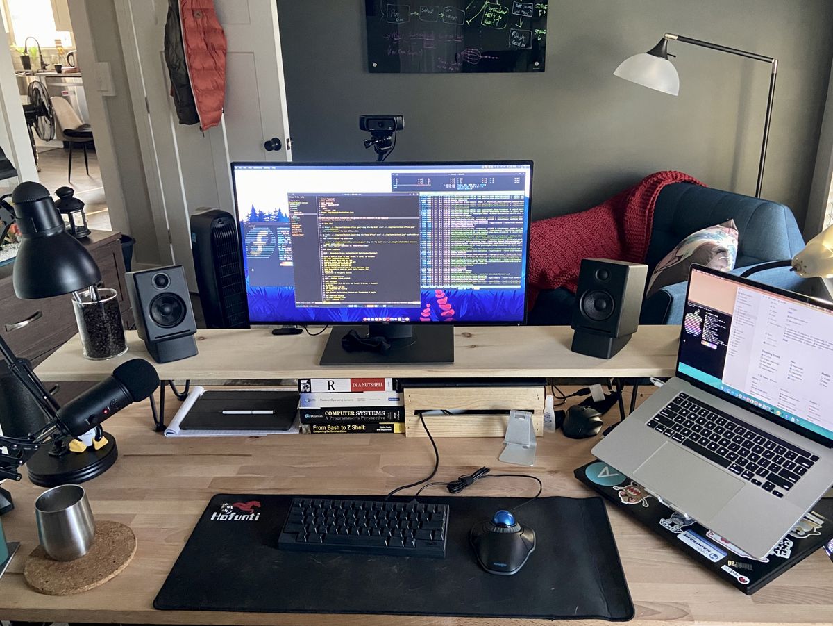 A wooden computer desk with wooden monitor shelf.