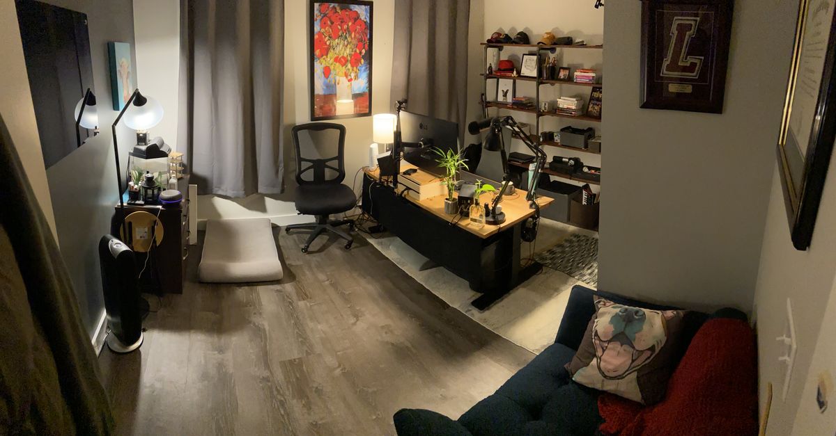 A home office with a desk in the middle and a wood and pipe shelf behind it