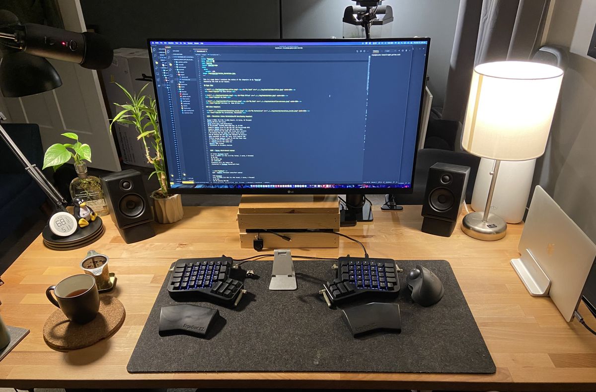 A wooden computer desk with large monitor and split keyboard