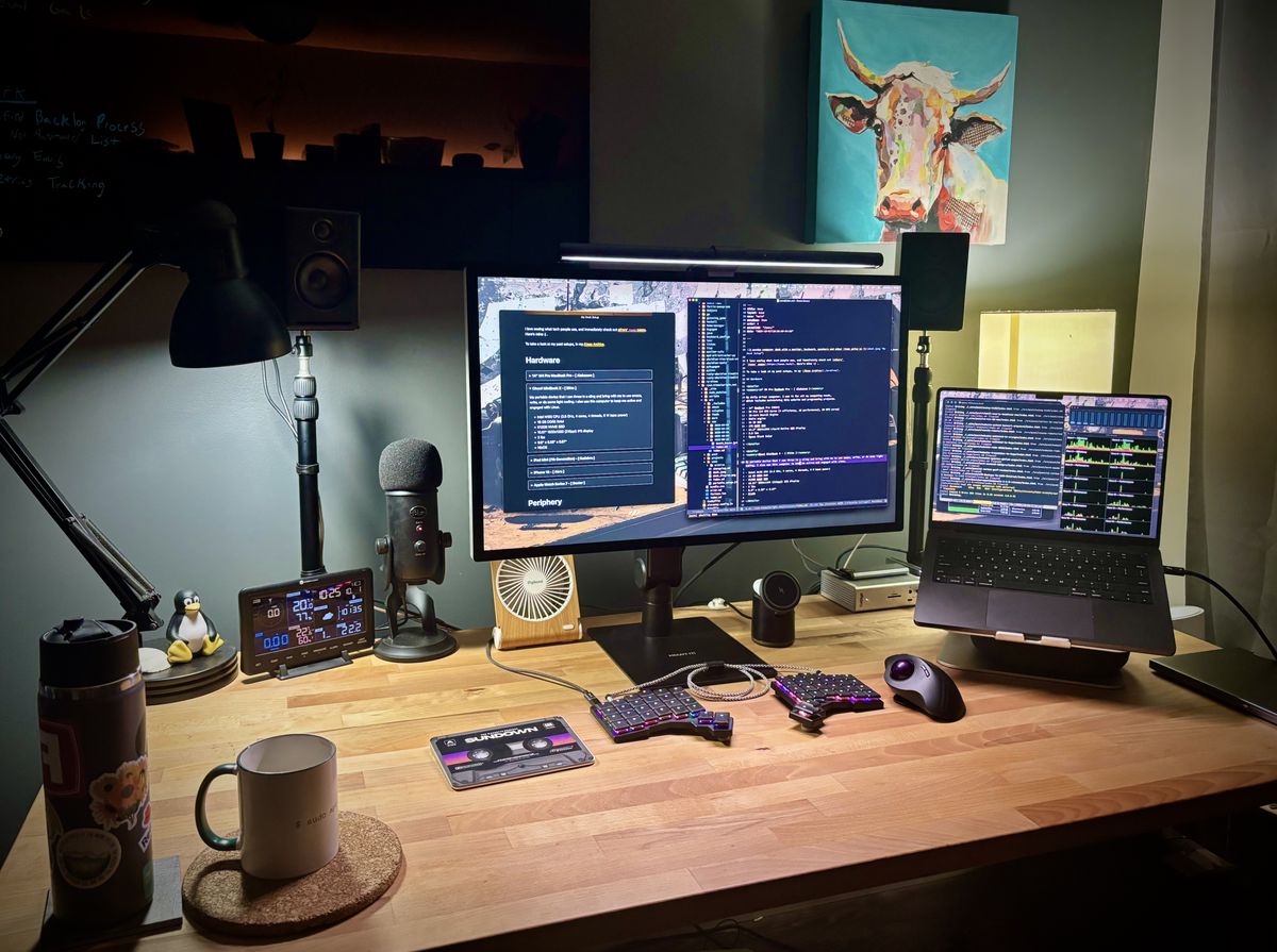 A wooden computer desk with a monitor, keyboard, speakers and other items going on it